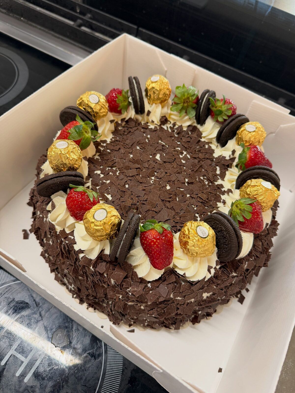 Torte mit Sahnetupfen, Erdbeeren und Schokolade, fertig verpackt zum Abholen